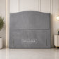 A gray upholstered headboard with a curved top