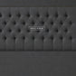 A dark gray upholstered headboard with a tufted button design
