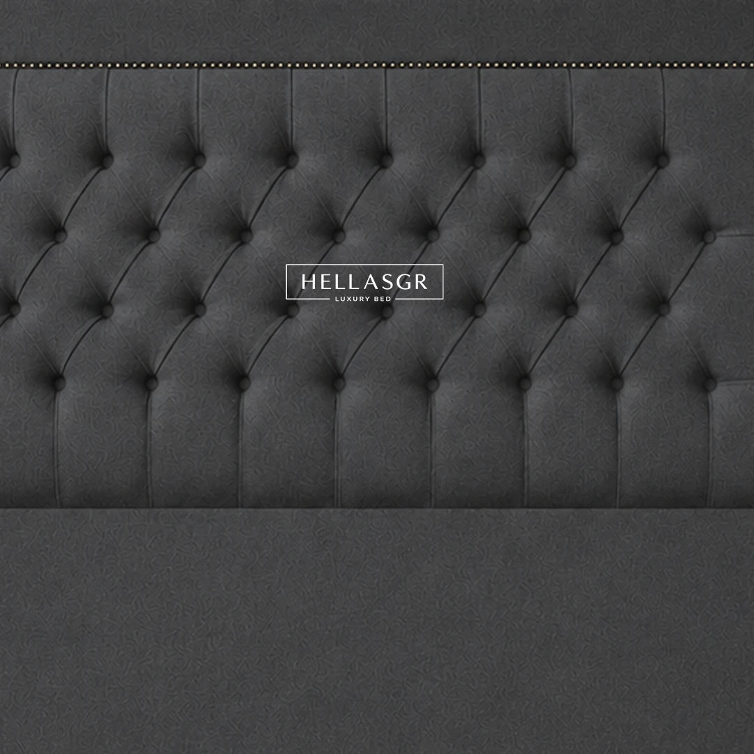 A dark gray upholstered headboard with a tufted button design