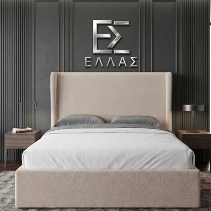 Beige upholstered Marina Elite bed with gray bedding against a dark paneled wall with a logo.