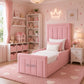 A pink upholstered single bed with a padded headboard and footboard
