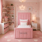 A pink upholstered single bed with a padded headboard and footboard
